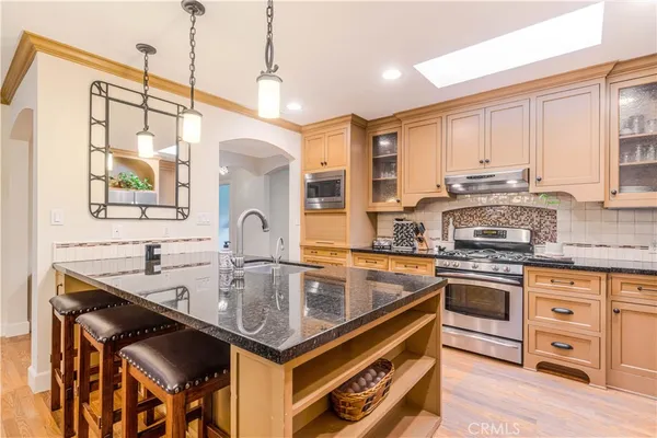 a kitchen with stainless steel appliances granite countertop a sink a stove and a wooden cabinets