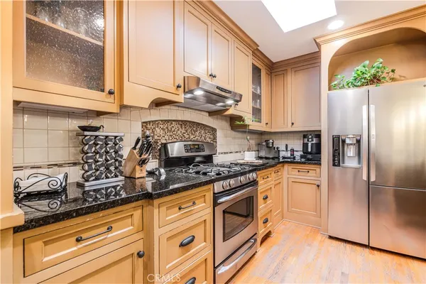 a kitchen with stainless steel appliances granite countertop a stove a sink and a refrigerator
