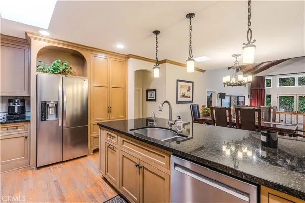 a kitchen with stainless steel appliances granite countertop a sink a refrigerator and a wooden floor
