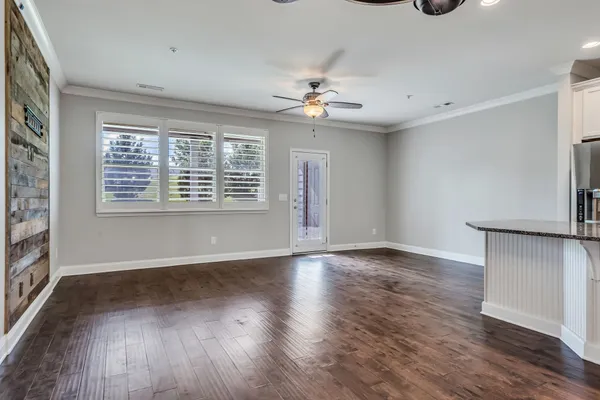 an empty room with wooden floor chandelier fan and windows