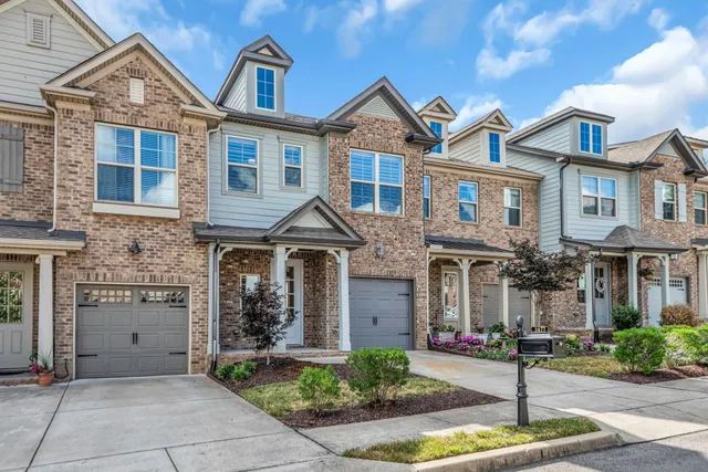 a front view of a house with garage and plants