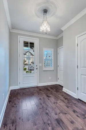 an empty room with wooden floor chandelier and windows