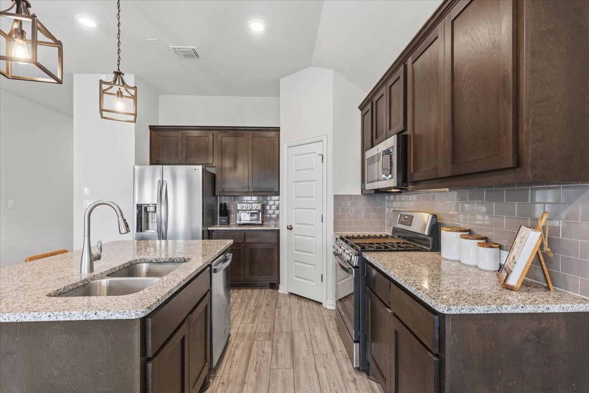 366 Cold Riv Run Kyle, TX 78640 - Photo 5 of 31 Kitchen featuring granite countertops, dark wood cabinetry, stainless steel appliances