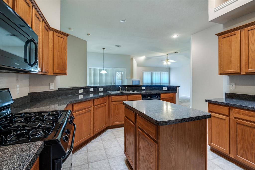 8530 Quicksilver Drive Dallas, TX 75249 - Photo 7 of 25 a kitchen with stainless steel appliances granite countertop a sink stove and microwave
