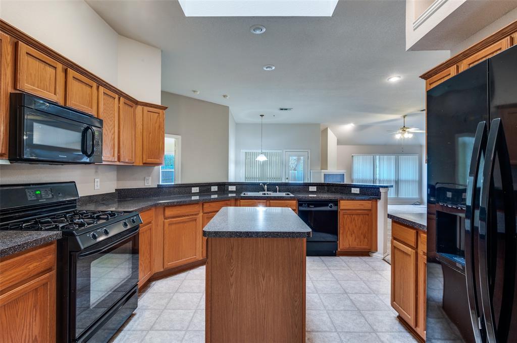 8530 Quicksilver Drive Dallas, TX 75249 - Photo 8 of 25 a kitchen with kitchen island granite countertop stainless steel appliances and wooden cabinets