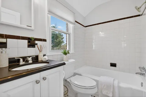 a bathroom with a granite countertop sink a toilet a mirror and shower