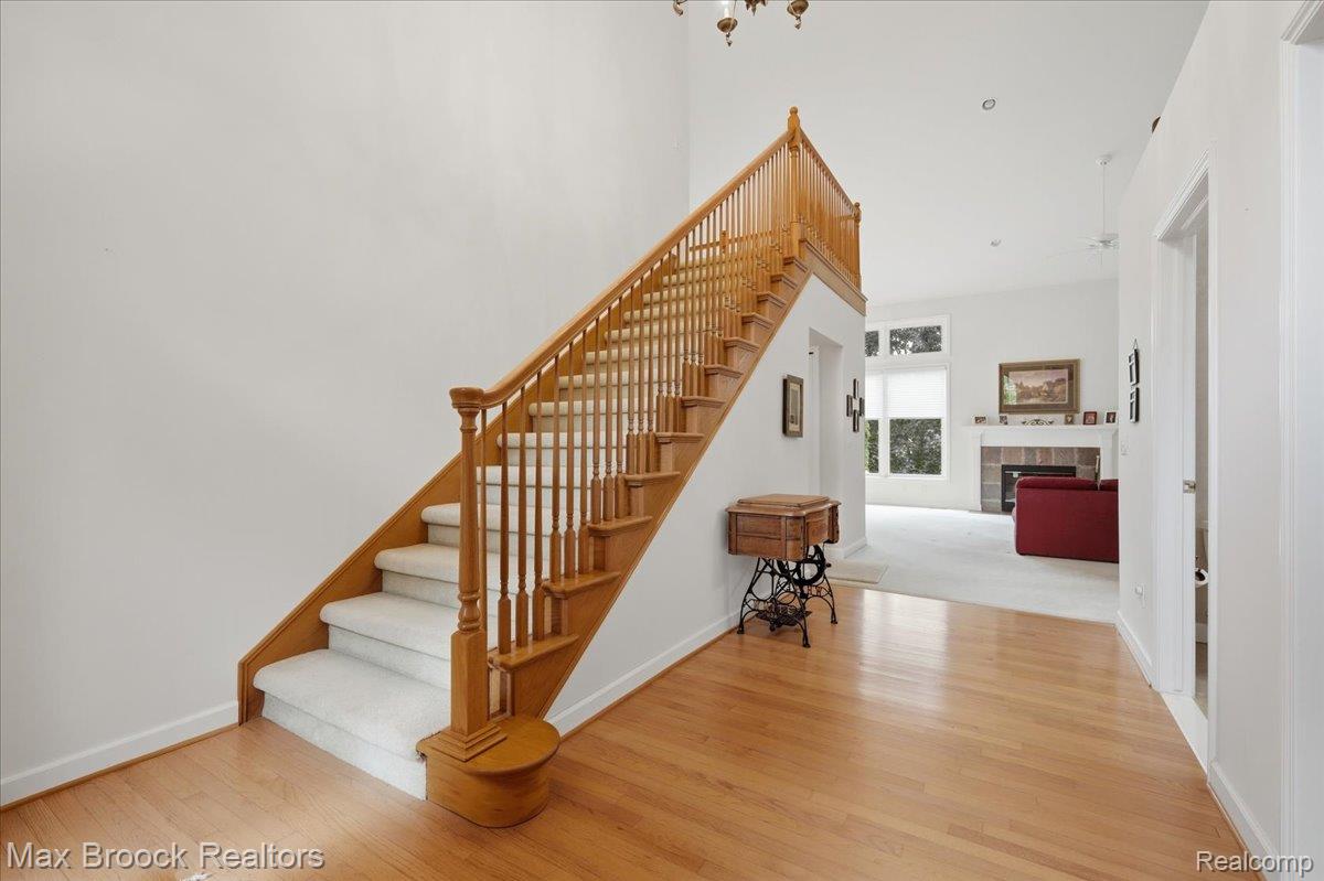 1731 Rico Road Commerce Township, MI 48382 - Photo 6 of 48 Hardwood flooring, two-story ceiling, wood staircase with carpeted treads, fireplace with mantel, and transom windows