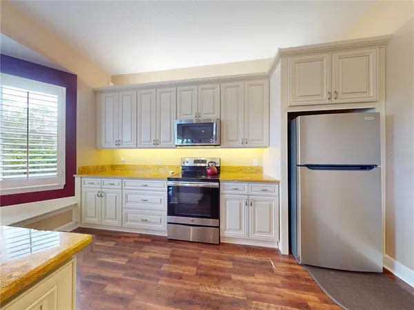 a large kitchen with stainless steel appliances granite countertop a stove and a large window