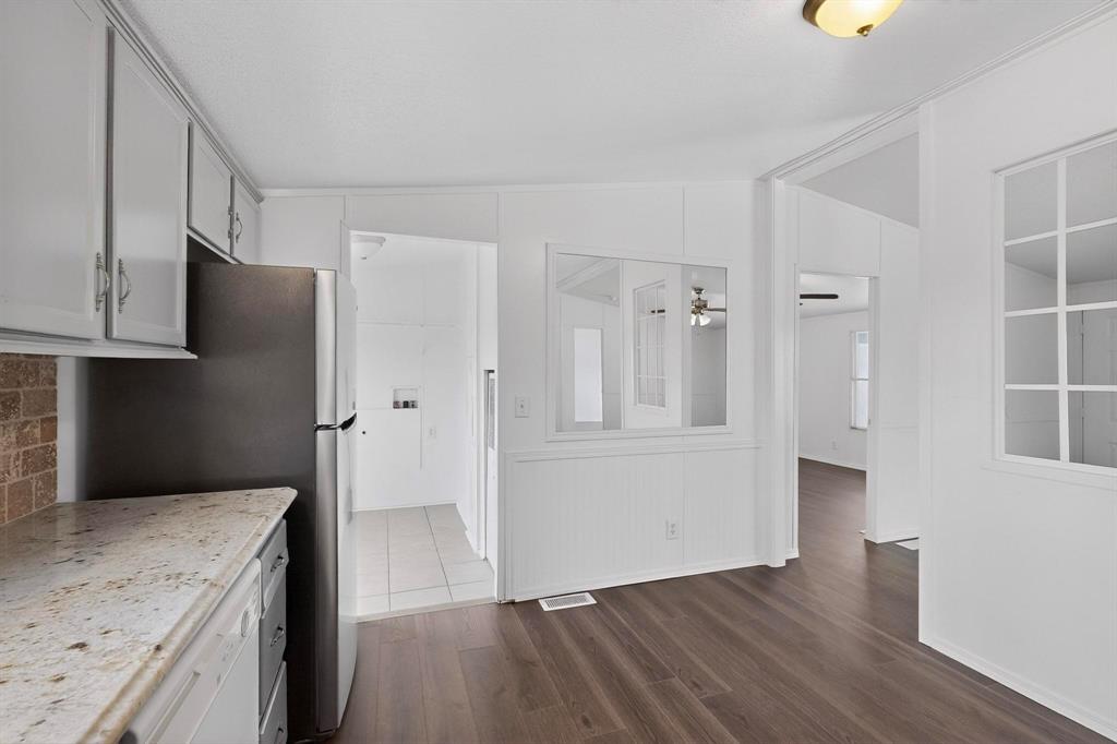 6553 Private Road 2270 Quinlan, TX 75474 - Photo 6 of 31 Kitchen featuring dark wood-style flooring, dishwasher, lofted ceiling, freestanding refrigerator, and light stone countertops