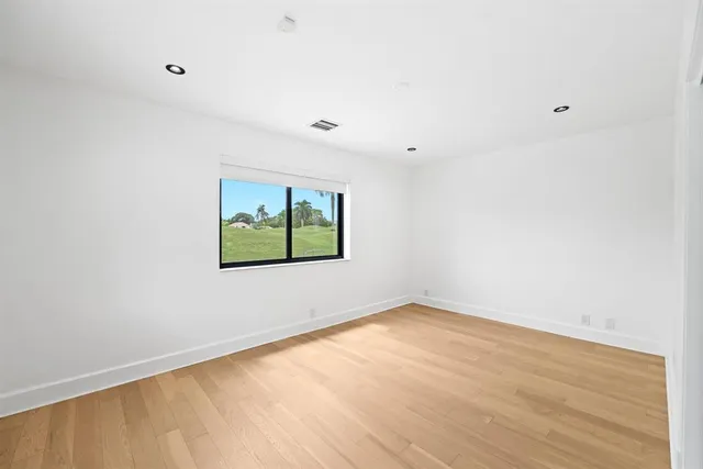 a view of an empty room with wooden floor and windows