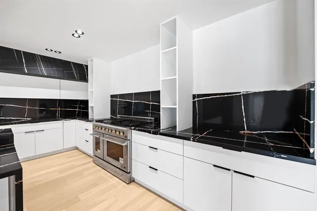 a kitchen with stainless steel appliances a stove a microwave and white cabinets