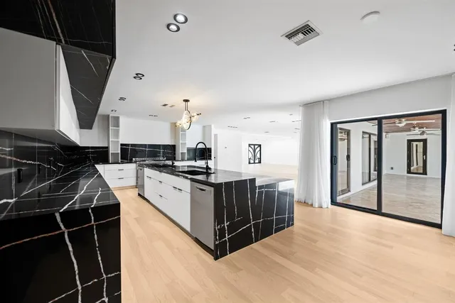 a kitchen with kitchen island a counter top space a sink stainless steel appliances and cabinets