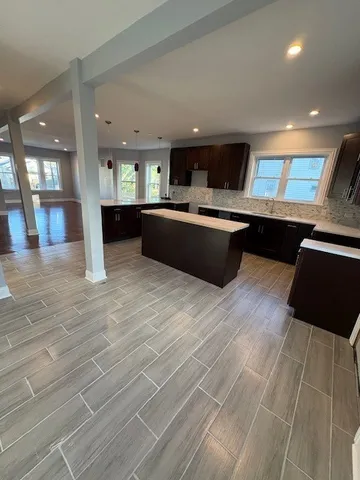 a view of an empty room with wooden floor and windows