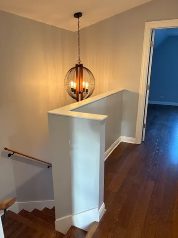 a view of a hallway with wooden floor and chandelier