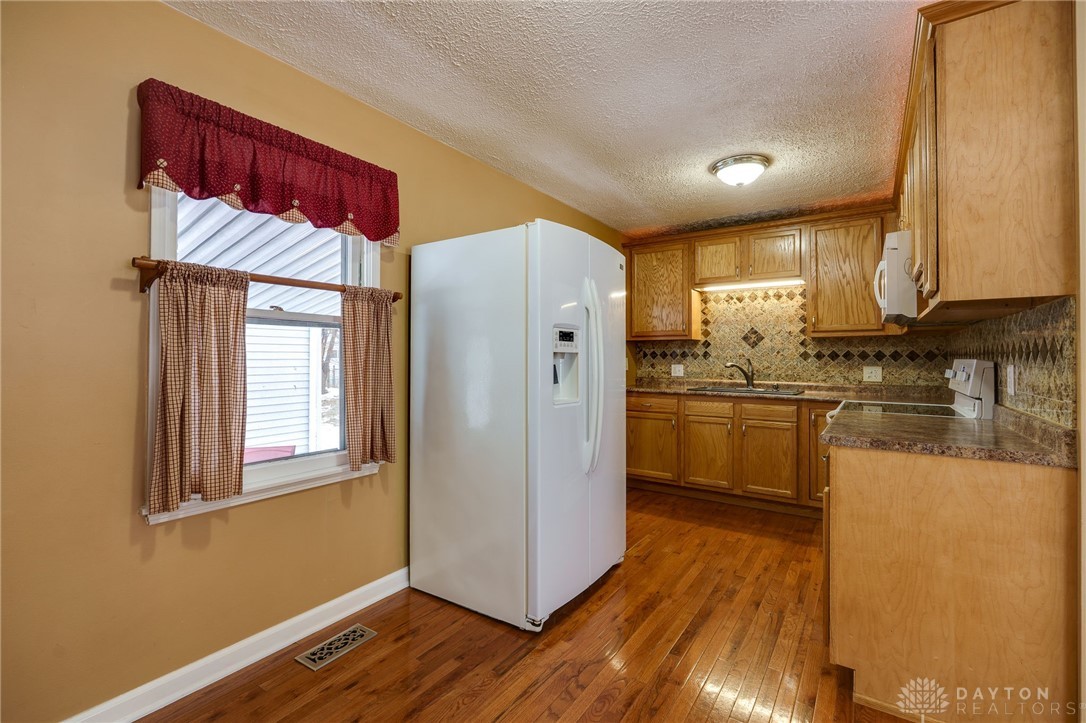 1817 Willamet Road Dayton, OH 45429 - Photo 7 of 37 Flooring in the kitchen is beautifully finished wood with wood cabinets, granite counters and a tile backsplash.