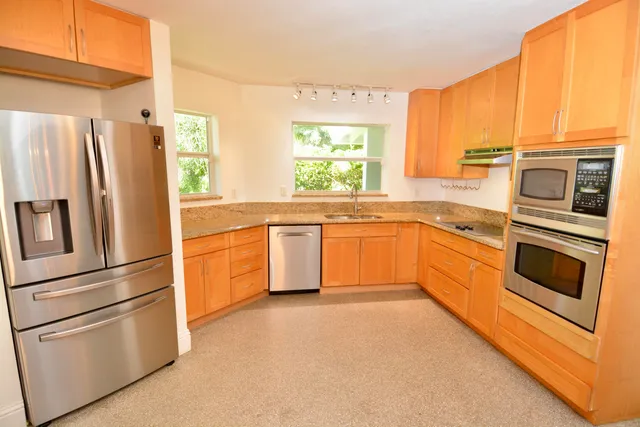 a kitchen with stainless steel appliances granite countertop a refrigerator a stove top oven a sink and dishwasher