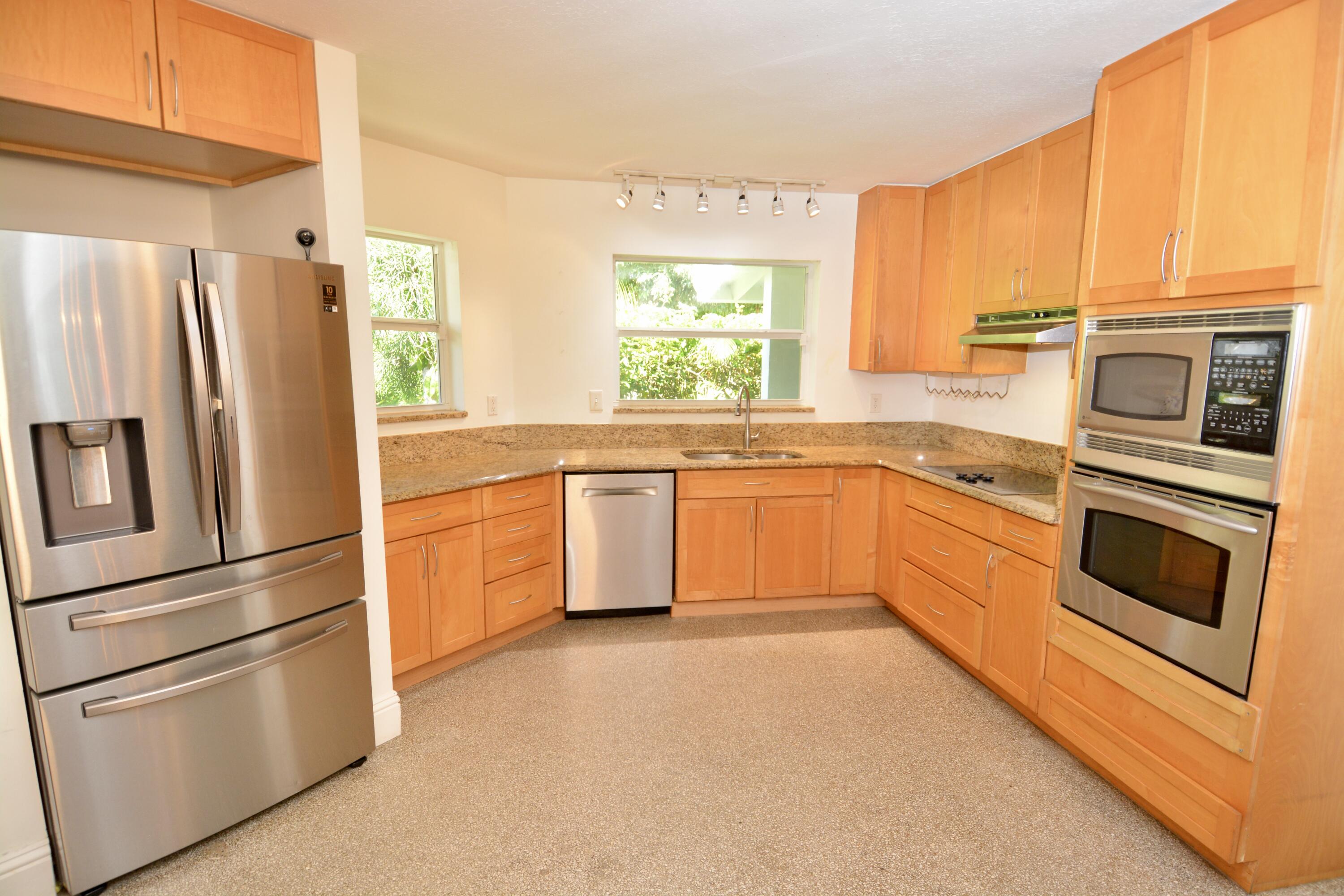 212 Kings Lynn Delray Beach, FL 33444 - Photo 19 of 53 a kitchen with stainless steel appliances granite countertop a refrigerator a stove a sink and white cabinets with wooden floor