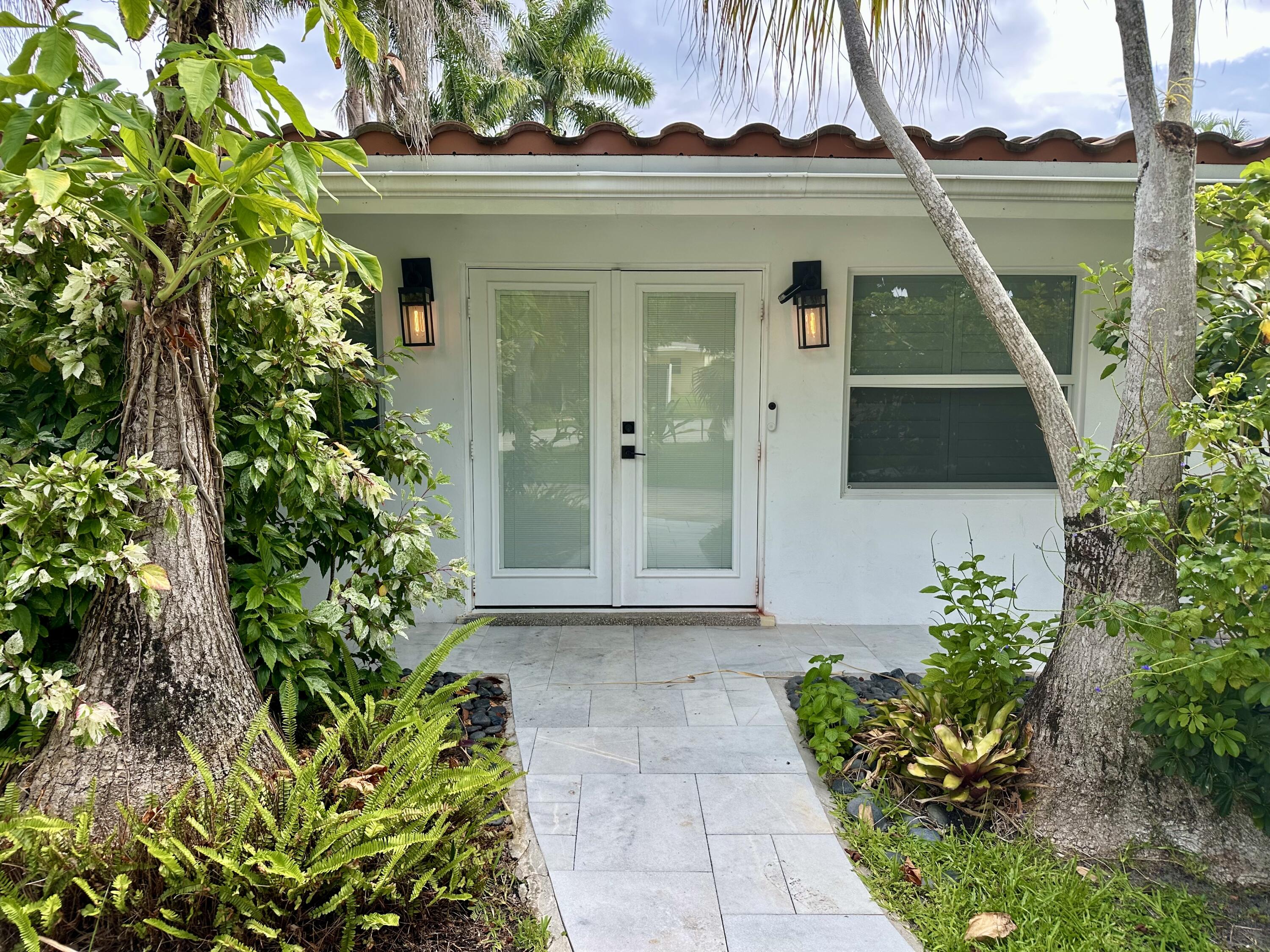 212 Kings Lynn Delray Beach, FL 33444 - Photo 2 of 53 a front view of a house with a garden