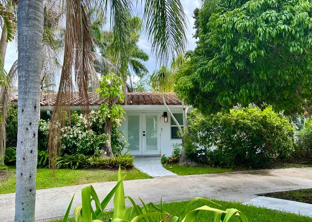 a view of a white house with a yard and potted plants