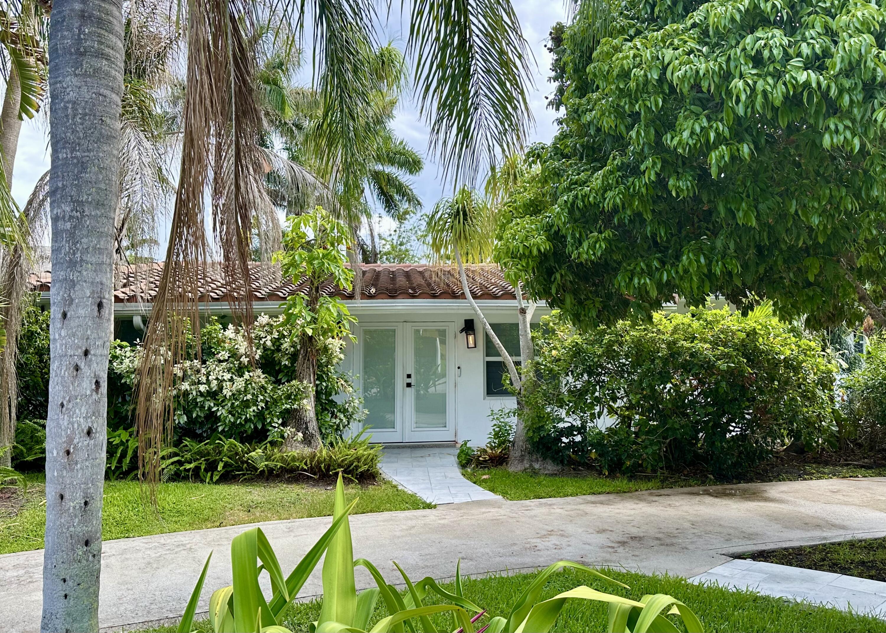 212 Kings Lynn Delray Beach, FL 33444 - Photo 3 of 53 a view of a white house with a yard and potted plants