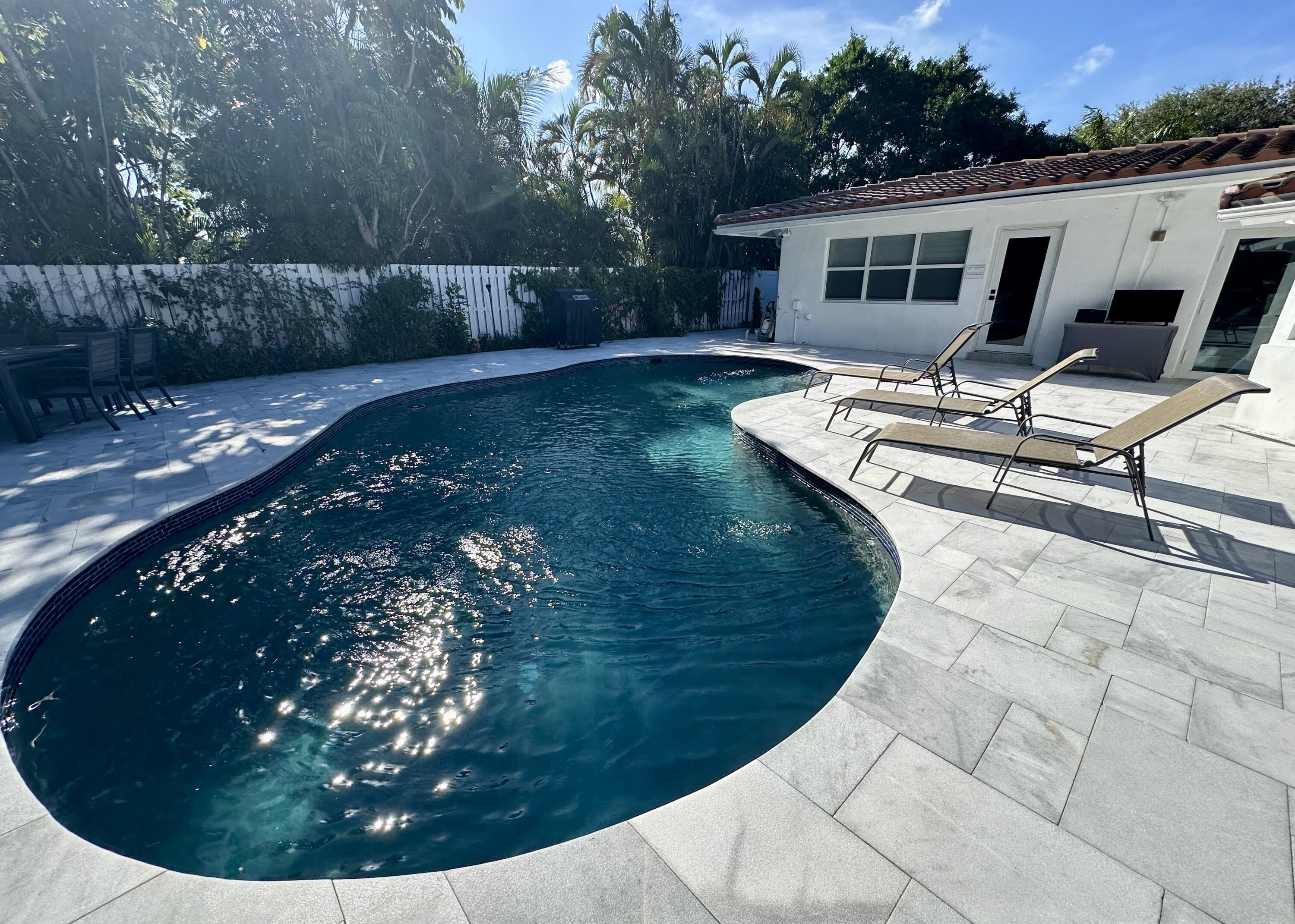 212 Kings Lynn Delray Beach, FL 33444 - Photo 39 of 53 a view of a backyard with table and chairs potted plants with wooden fence