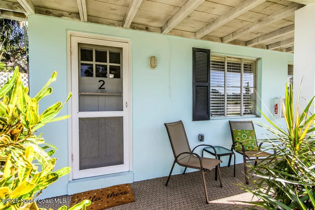 a balcony with table and chairs and potted plants