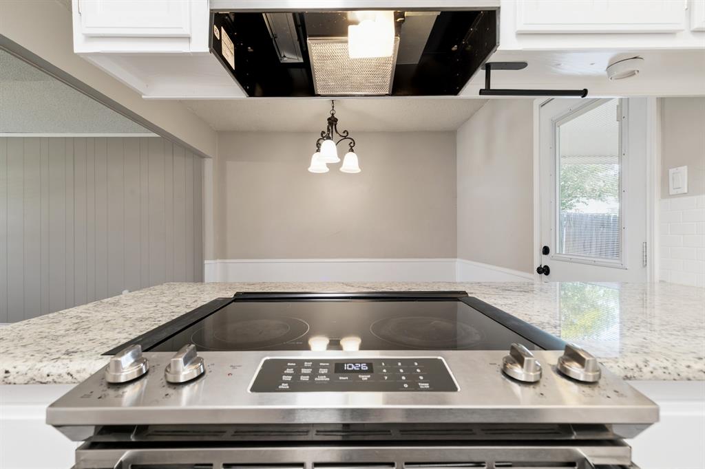6612 Patsy Lane Watauga, TX 76148 - Photo 17 of 32 Built-in stainless steel electric range with a black ceramic cooktop, set within a light-toned countertop