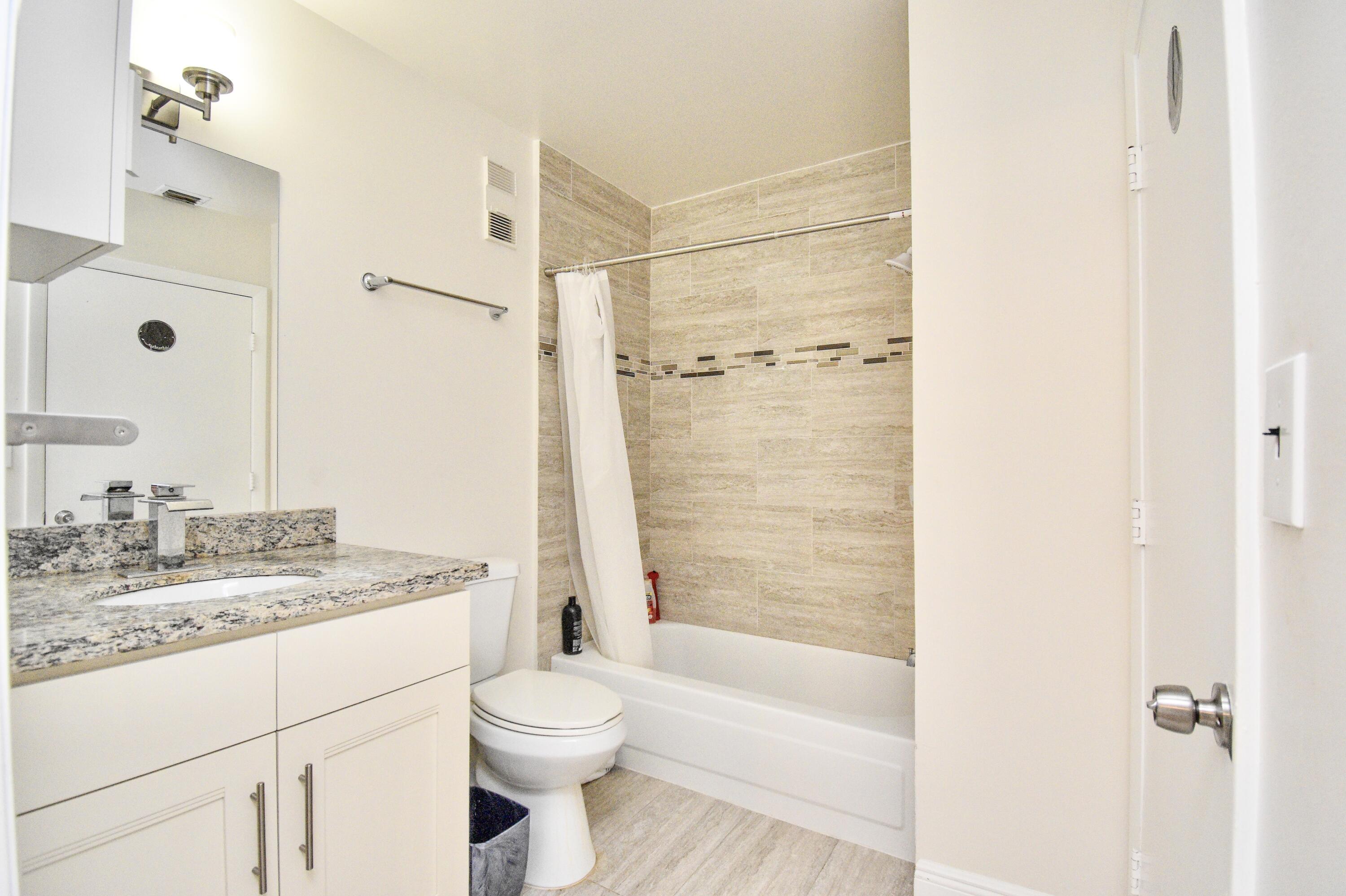 6053 Old Court Road, Unit 308 Boca Raton, FL 33433 - Photo 17 of 22 a bathroom with a granite countertop sink a toilet and shower