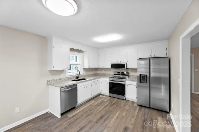 a kitchen with cabinets stainless steel appliances and wooden floor