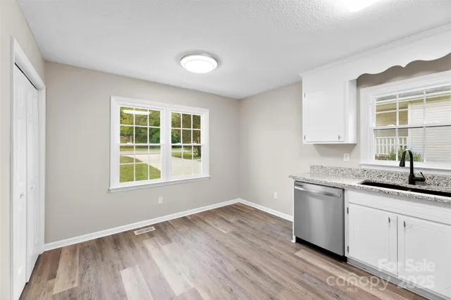 a kitchen with a sink cabinets wooden floor and a window