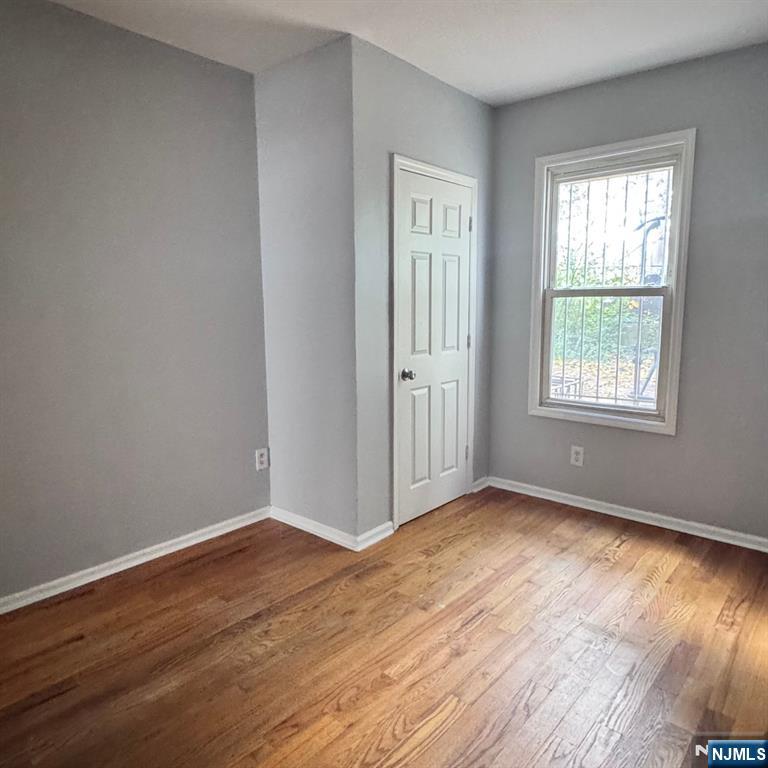97 Clinton Place Newark, NJ 07108 - Photo 7 of 9 a view of an empty room with wooden floor and a window