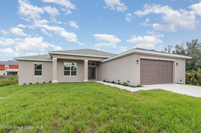 a front view of house with yard and trees in the background