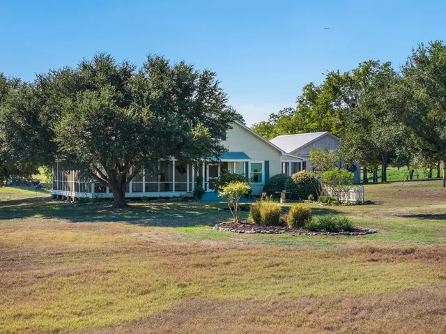 a front view of a house with garden and trees