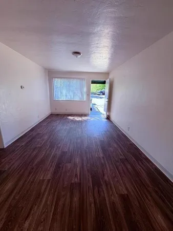 a view of an empty room with wooden floor and a window