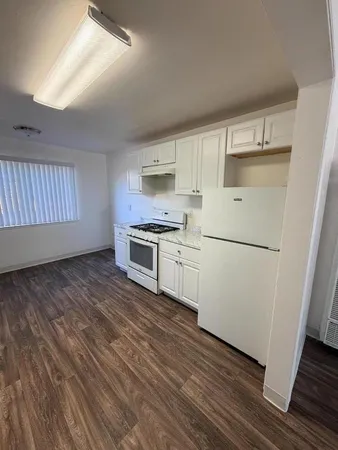 a kitchen with wooden floors and white appliances