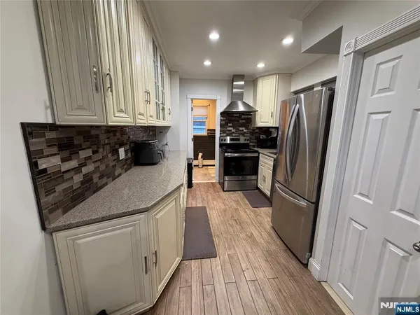 a kitchen with stainless steel appliances a refrigerator a sink and wooden floors