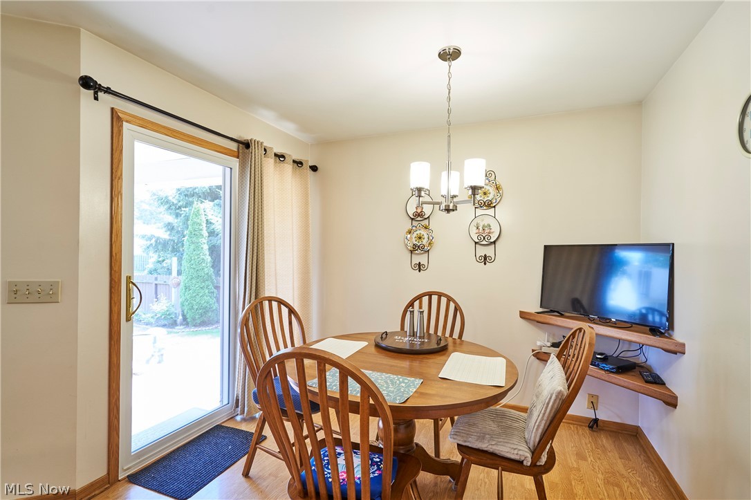 1963 Haines Road Madison, OH 44057 - Photo 15 of 34 Dining area featuring wood-finish flooring, a contemporary ceiling chandelier, and a sliding glass patio door with wood trim