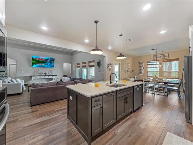 14845 Norma Jane Lane Beaumont, TX 77713 - Photo 7 of 35 a large kitchen with stainless steel appliances a stove a sink dishwasher and a dining table with wooden floor