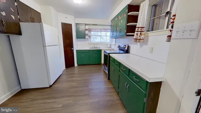 a kitchen with stainless steel appliances a refrigerator and a wooden floor