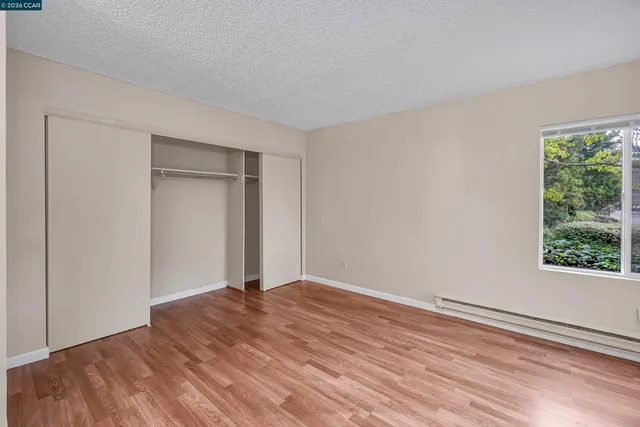 a view of empty room with wooden floor and fan