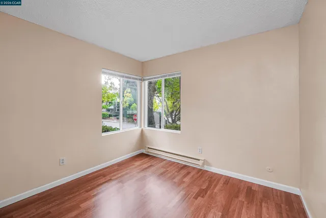 an empty room with wooden floor and windows