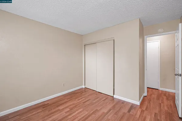 a view of an empty room with wooden floor and closet
