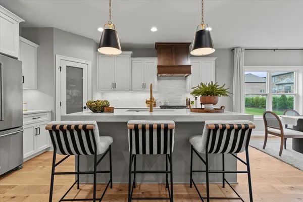 a dining room with wooden floor a chandelier a glass table and chairs