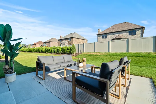 a view of a patio with table and chairs under an umbrella with a yard