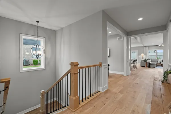 a view of a hallway with workspace and bedroom with wooden floor
