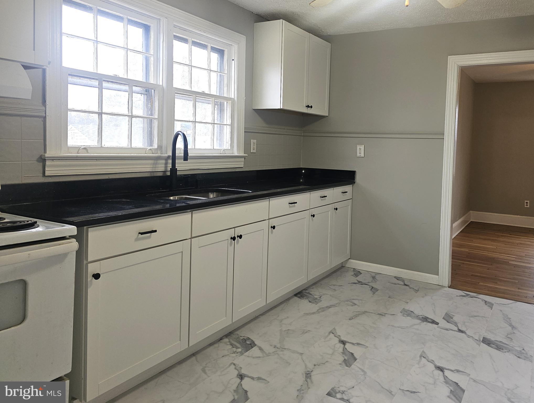 1431 Warrenton Road Fredericksburg, VA 22406 - Photo 6 of 25 a kitchen with granite countertop white cabinets and window