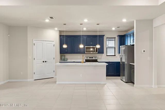 a large white kitchen with a refrigerator a stove top oven and cabinets