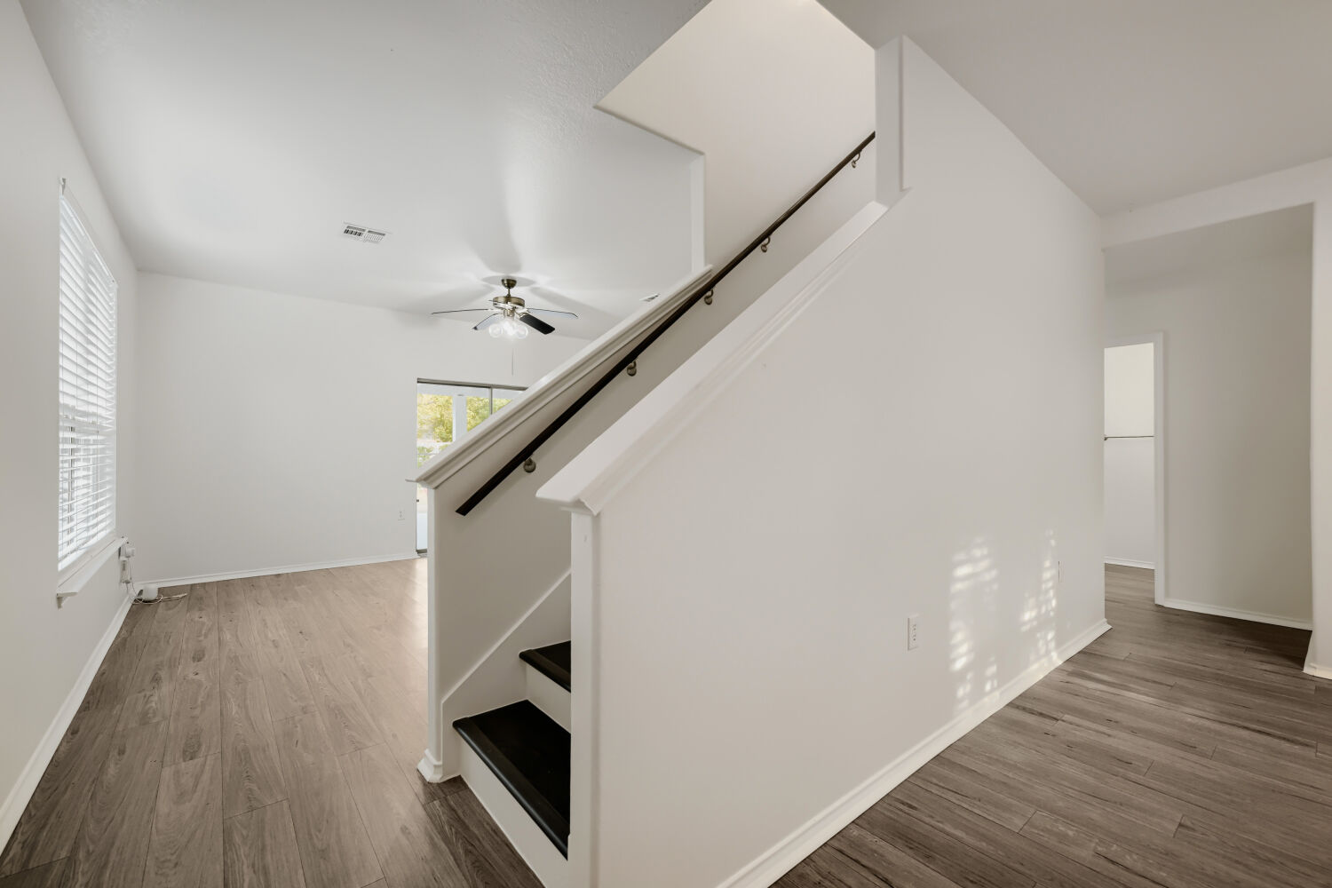 4508 Peach Grove Road Austin, TX 78744 - Photo 9 of 22 Gleaming wood-look floors complement clean white walls framing a central staircase.