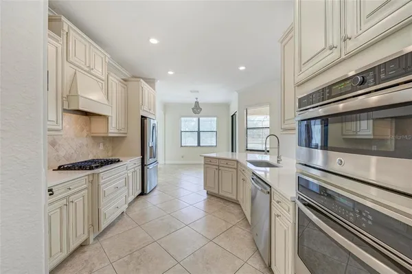 a view of an empty room and a kitchen with wooden floor