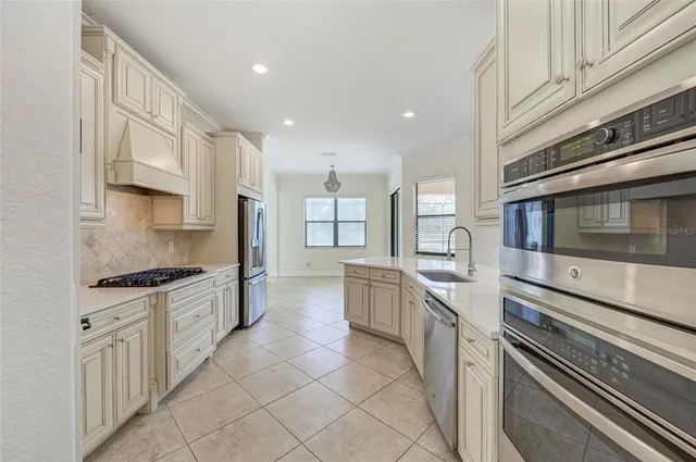 a view of an empty room and a kitchen with wooden floor